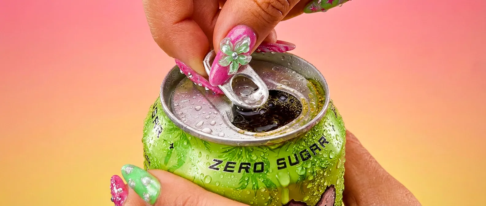 A hand with glossy Bratz-style nails cracking open a green Monster x Bratzmode Zero Sugar can, condensation across the can